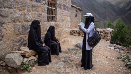 A community health worker visits a family to conduct a physically distant information session