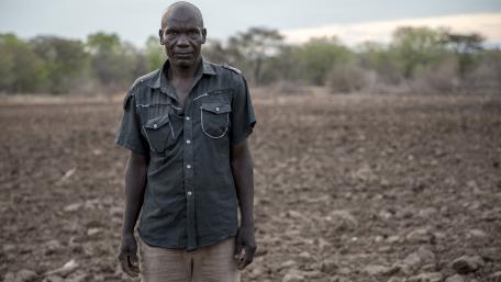 A farmer standing in front of a dry piece of land