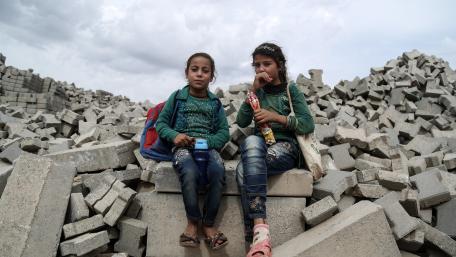 Two girls sitting on top of rubble