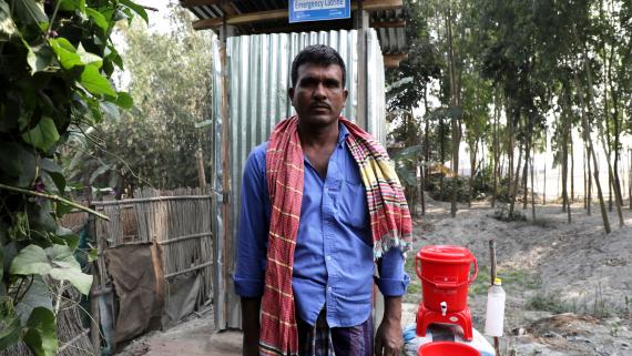 A man stands in front of a latrine
