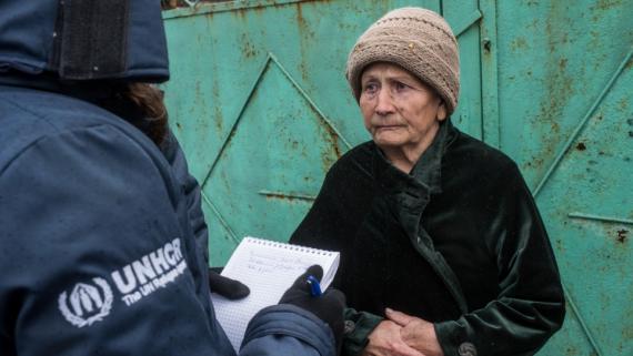 An old woman listens to a humanitarian worker