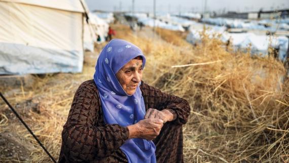 An old woman sits on a refugee camp