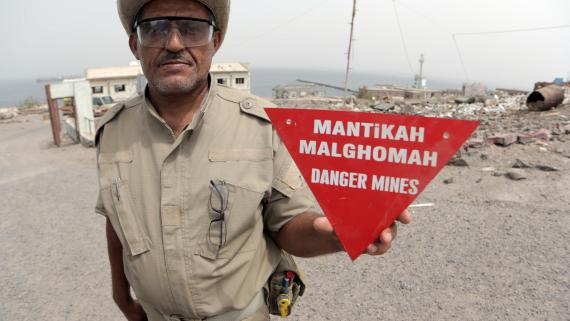 A man holds a mine warning sign