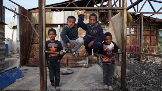 Four young boys in a destroyed warehouse pose for a picture