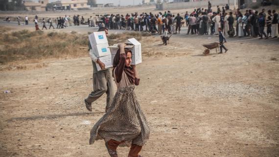 A girl and a boy carry boxes with emergency assistance