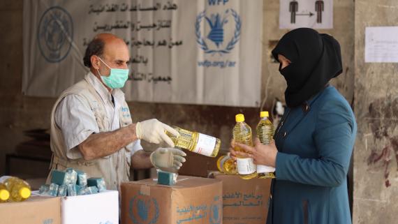 A man distributes oil bottles to a woman