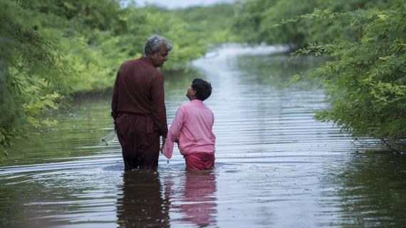 Father and son walk across flood water