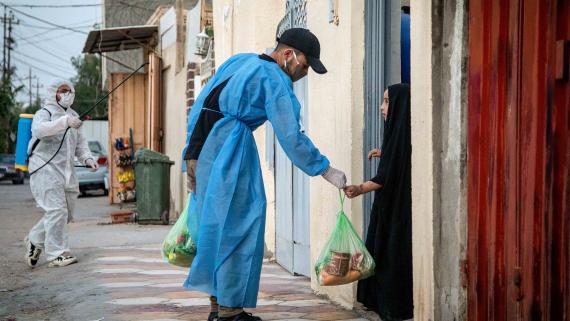 A man delivers a bag of food to a girl at her home
