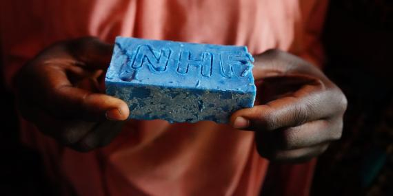 A girl holds a soap bar with the inscription NHF