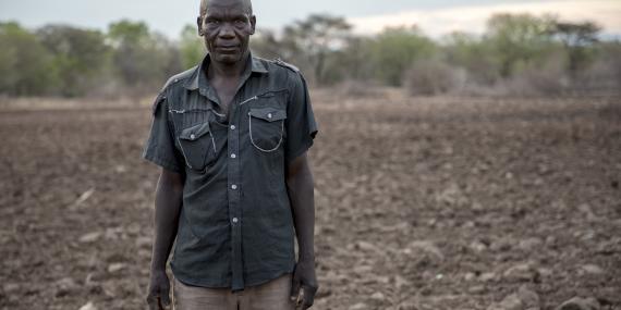 A man stands in front of a dry field