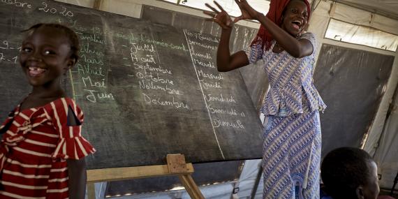 A teacher plays with her pupils in front of the blackboard